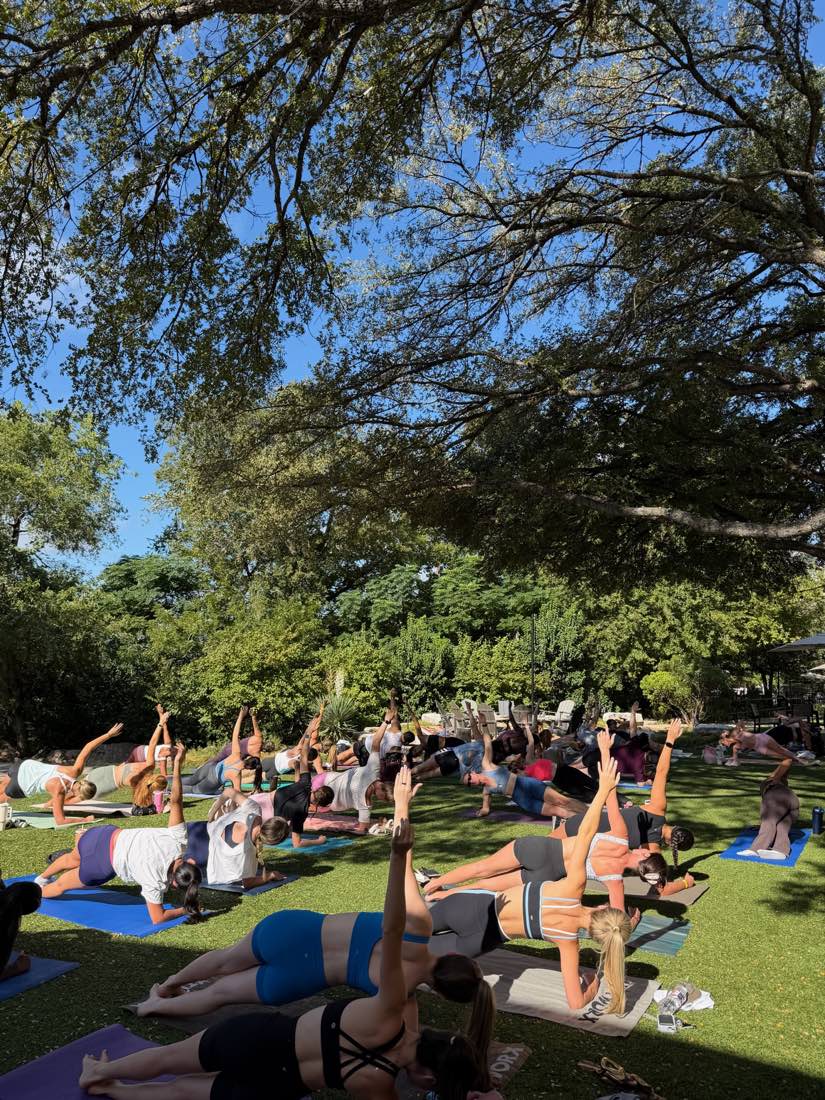 A large outdoor pilates class on the grass at an AGC wellness event